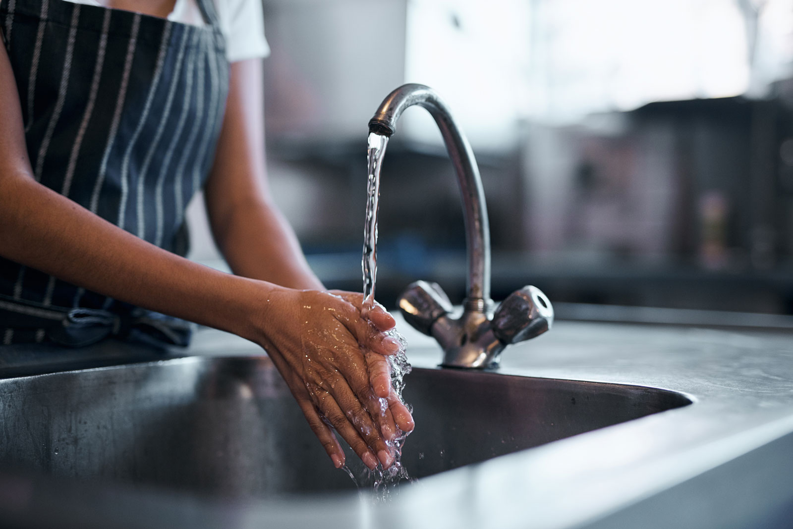 A woman washing her hands with softened water from the kitchen faucet