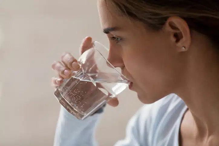 A woman drinking a glass of softened water