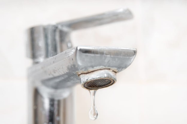 A closeup of a faucet with limescale buildup from hard water. 
